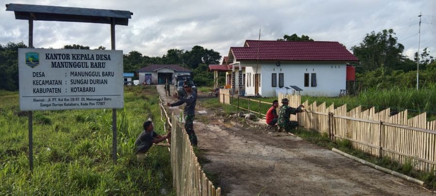 Personel TMMD ke 112 bantu mengecat pagar kantor desa